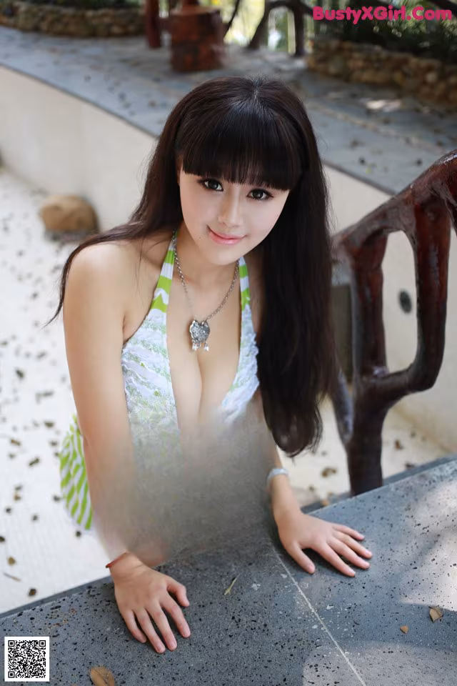 A woman in a green and white bikini posing for a picture.
