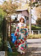 A woman in a colorful kimono standing on a sidewalk.