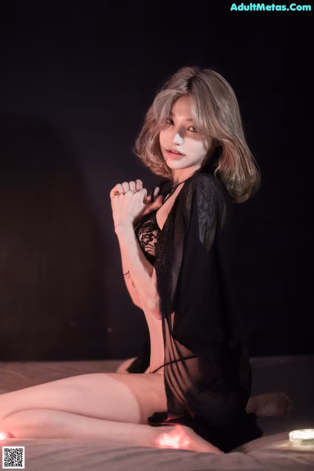 A woman in a black lingerie sitting on a bed.