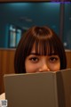 A woman is reading a book in front of her face.