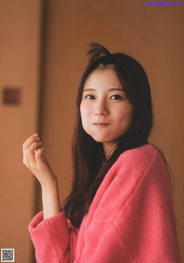 A woman in a pink sweater is posing for a picture.
