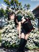 A girl with a backpack standing in front of a bush of flowers.