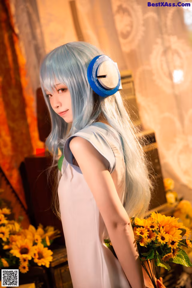 A woman with long blue hair holding a bunch of flowers.