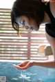 A woman in a black tank top is pouring water into a pool.