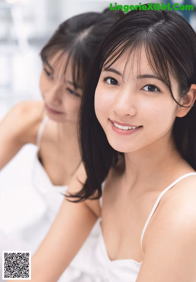 A woman in a white dress sitting next to another woman.