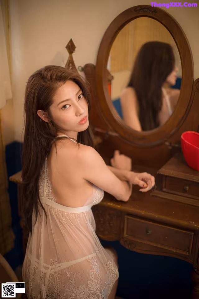 A woman in a white lingerie sitting in front of a mirror.