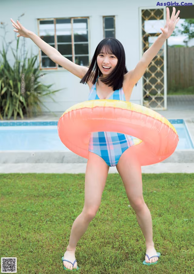 A woman in a bathing suit holding an inflatable ring.