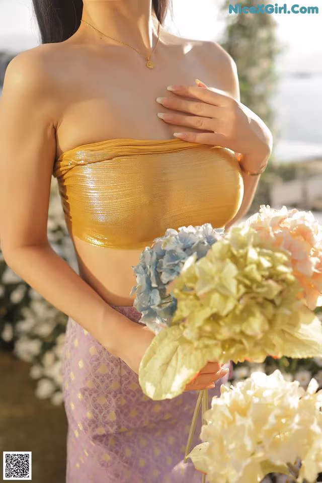 A woman in a yellow top holding a bouquet of flowers.