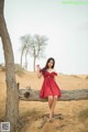 A woman in a red dress sitting on a tree branch.