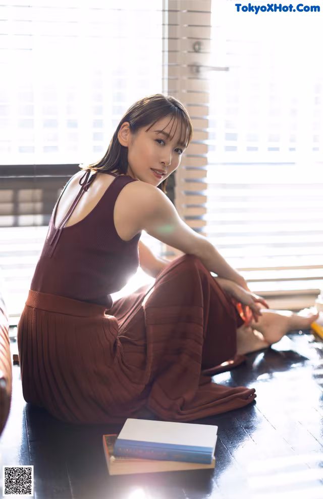 A woman sitting on the floor next to a book.