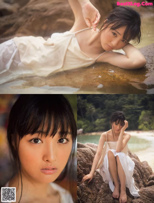 A woman in a white dress sitting on a rock by the water.