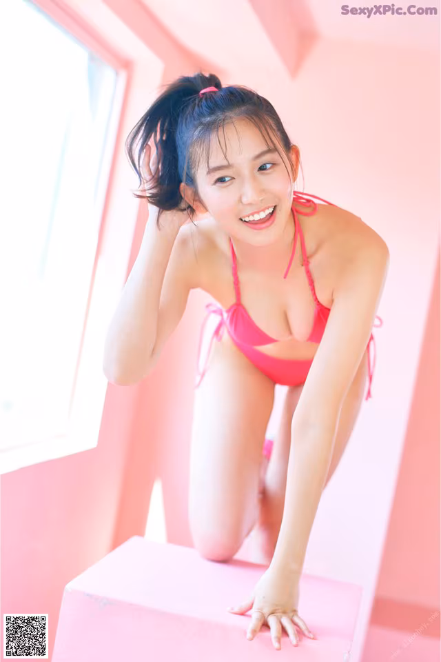 A woman in a pink bikini posing for a picture.