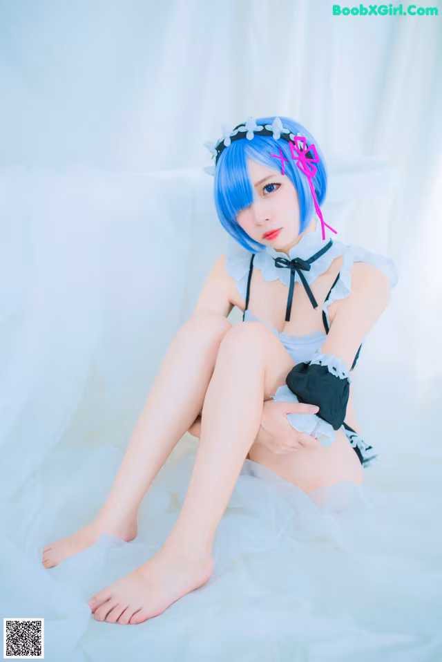 A woman with blue hair sitting on a bed.