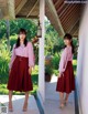 A woman wearing a pink blouse and a red skirt.