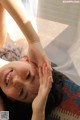 A woman laying on a bed with her hands on her head.