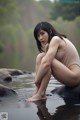 A woman sitting on a rock in the water.