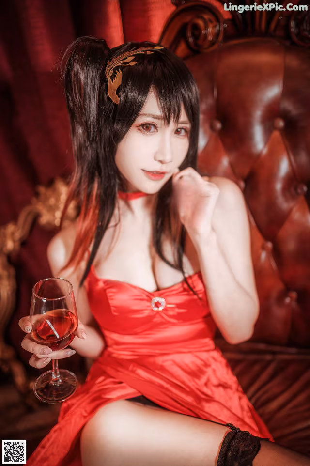 A woman in a red dress holding a glass of wine.