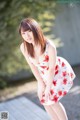 A woman in a white dress with red flowers on it.