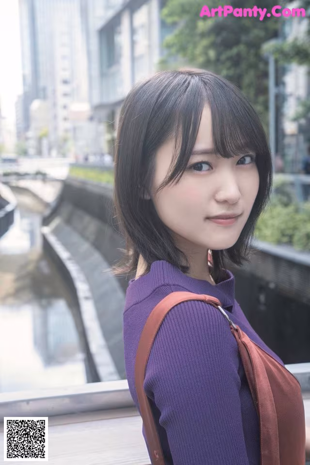 A woman in a purple sweater is posing for a picture.