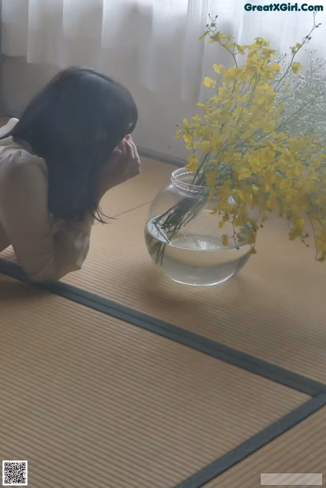 A woman laying on the floor next to a vase of flowers.