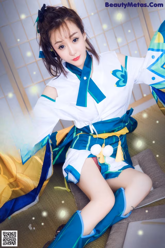 A woman in a blue and white outfit sitting on a bed.