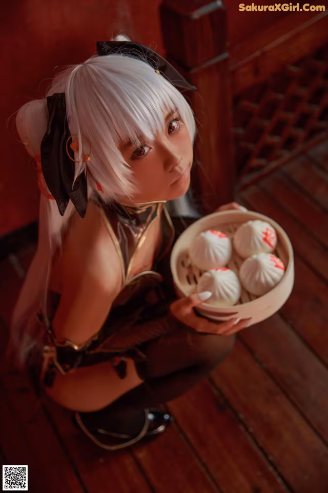 A woman holding a bowl of dumplings on a wooden floor.