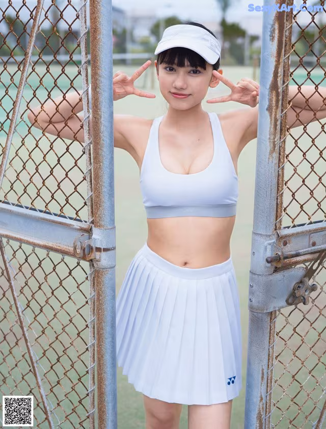 A woman in a white tennis outfit posing for a picture.
