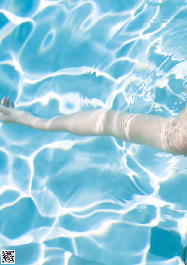 A woman floating in a swimming pool with her arms outstretched.