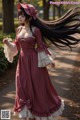 A woman in a long dress and hat walking down a path.