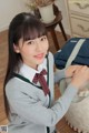 A young woman in a school uniform holding a backpack.