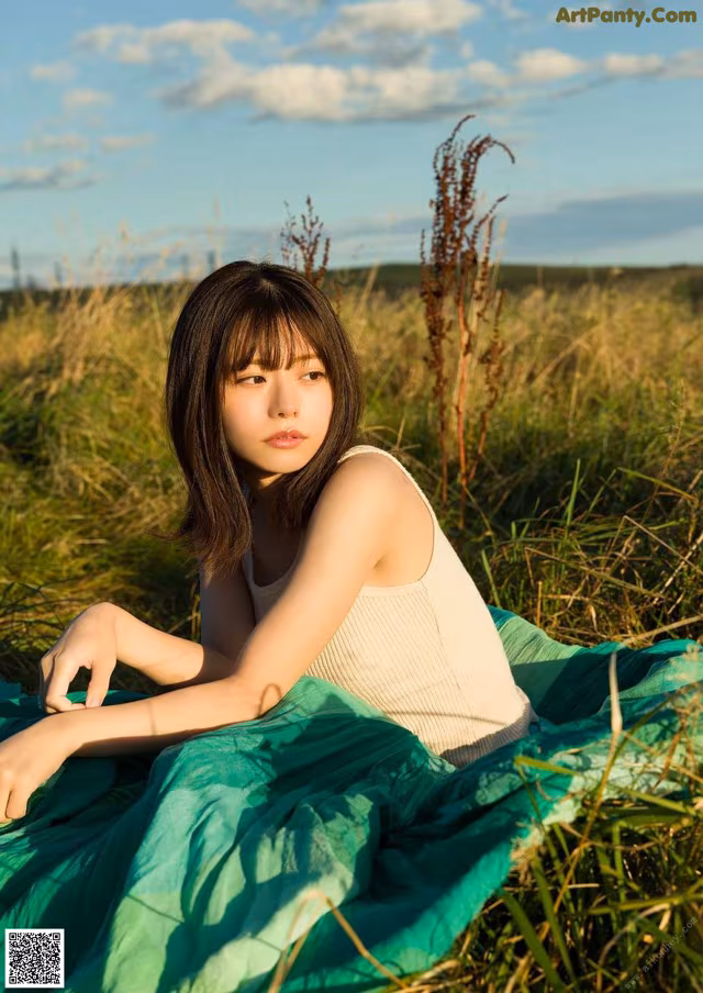 A woman sitting in a field of tall grass.
